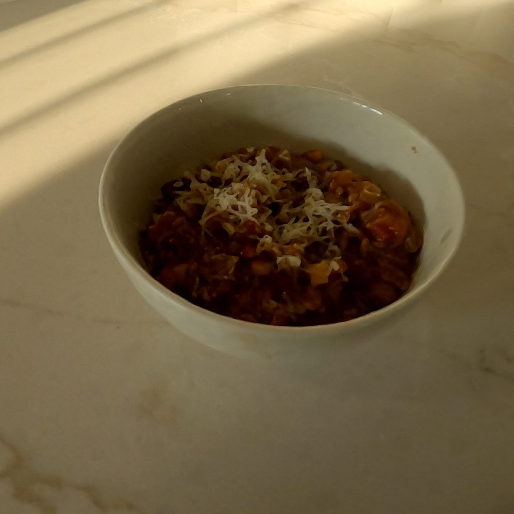 A bowl of homemade chili con carne topped with grated cheese
